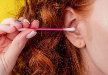 woman holds Q-tip close to ear