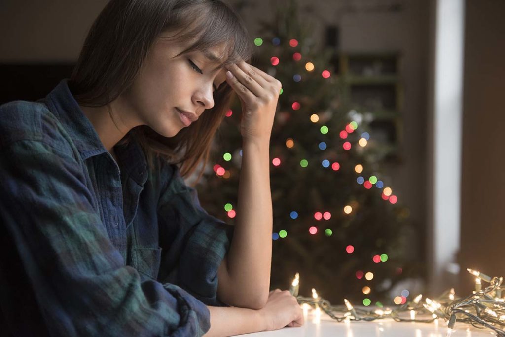 woman looking sad with Christmas tree in background