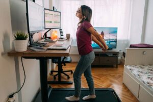 Woman at home office is walking on under desk treadmill