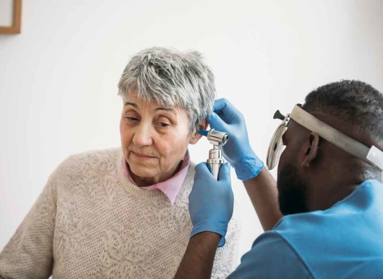 A woman having her ear checked for tinnitus with a medical instrument.