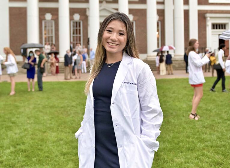 Christine Huynh in white coat in front of UVA School of Medicine