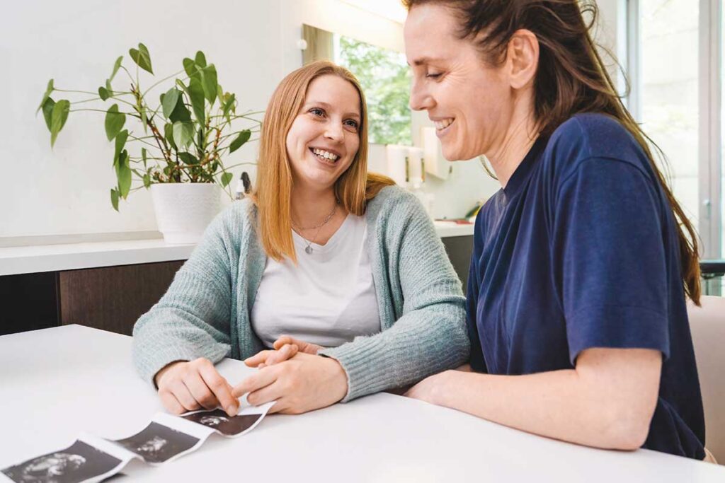 A lesbian couple enjoys ultrasound photos of coming baby. LGBTQ+ friendly healthcare is inclusive of all.