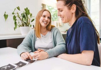 A lesbian couple enjoys ultrasound photos of coming baby. LGBTQ+ friendly healthcare is inclusive of all.