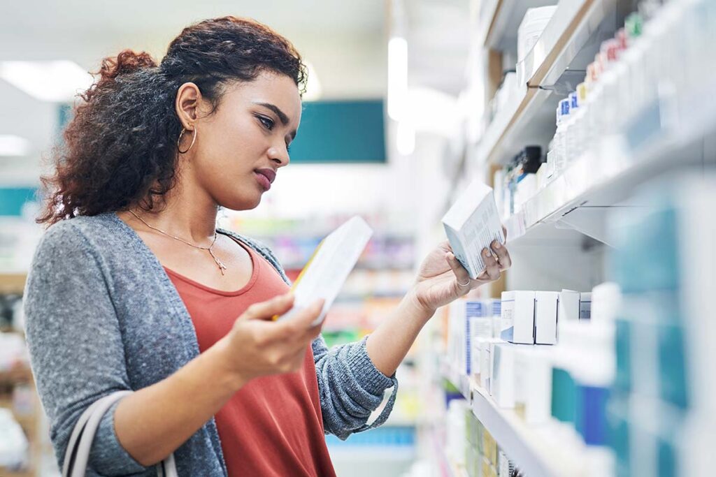 woman looks at 2 medications at a pharmacy
