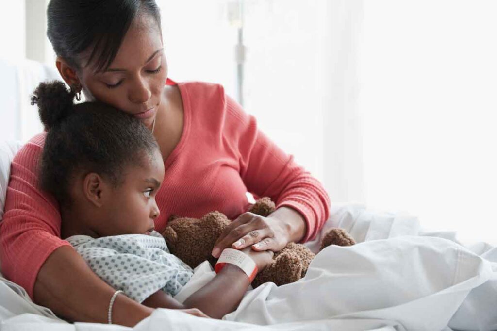 A mother laying with her daughter in a hospital bed