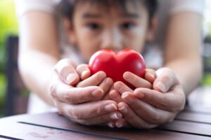 Parent's and child's hands both hold a heart