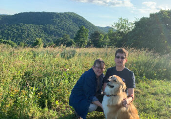 Stage 4 cancer survivor Anne with her husband and dog on their yard near the mountains