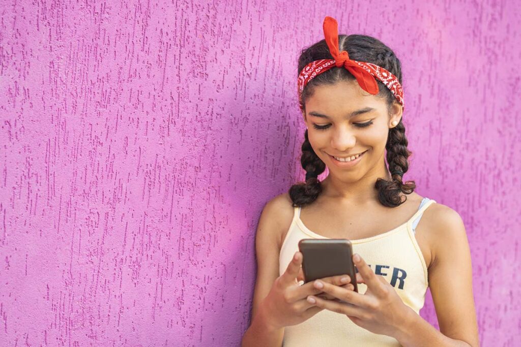 Young girl smiles at something she's seeing on her smartphone