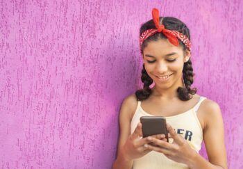 Young girl smiles at something she's seeing on her smartphone