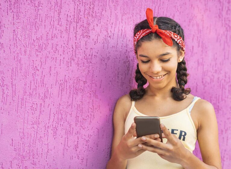 Young girl smiles at something she's seeing on her smartphone