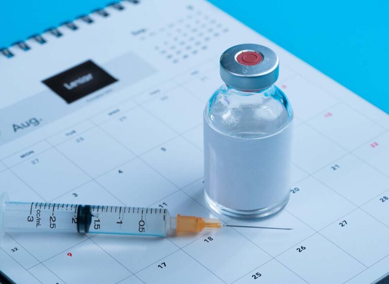 Vaccine booster rests on calendar