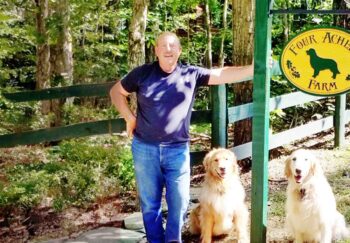 Barry, an esophageal cancer survivor, standing with two dogs outdoors