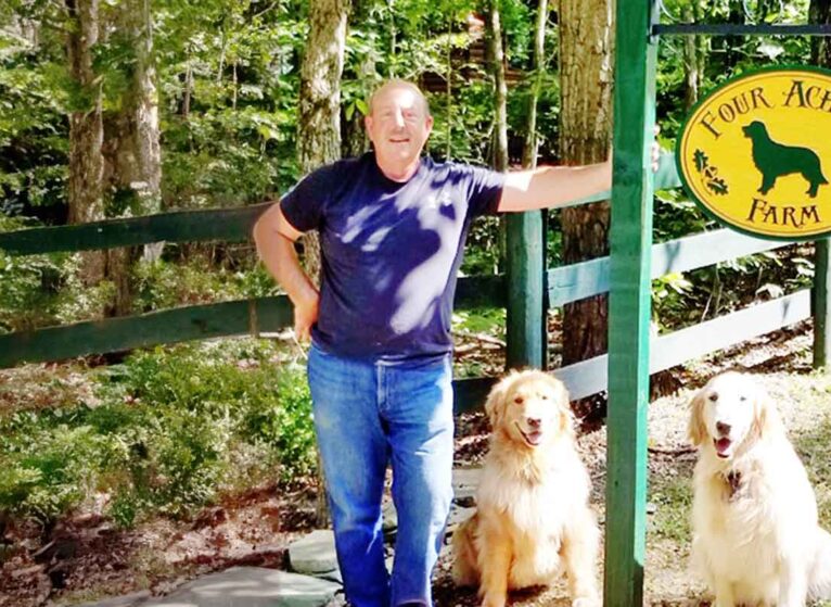 Barry, an esophageal cancer survivor, standing with two dogs outdoors