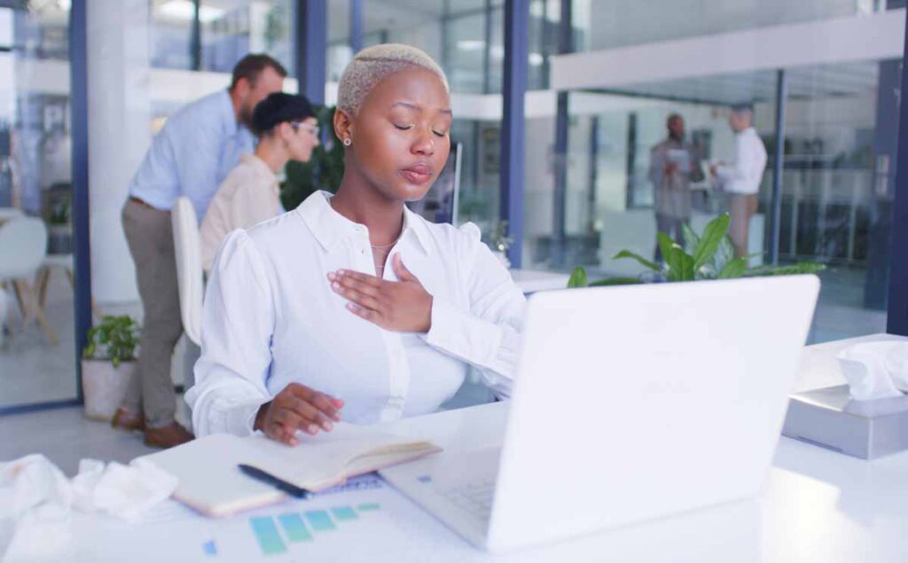 A young professional woman at the office with her hand on her chest