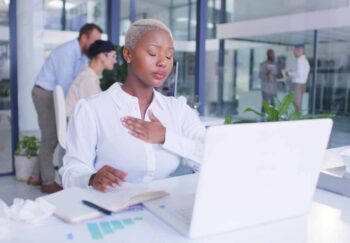 A young professional woman at the office with her hand on her chest