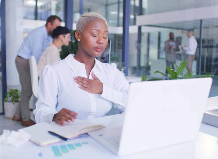 A young professional woman at the office with her hand on her chest