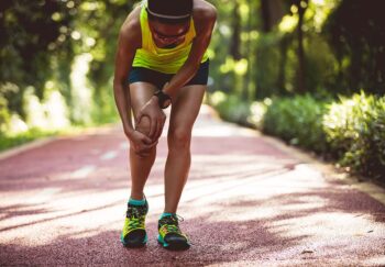 a runner stops and grabs her leg