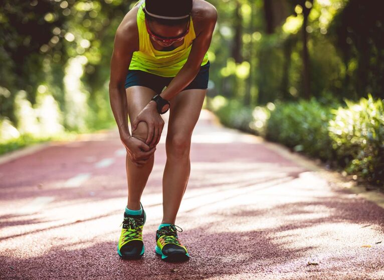 a runner stops and grabs her leg