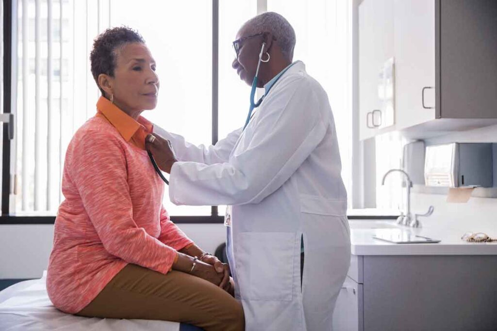 A woman doctor checking the heart of a patient with a stethoscope.