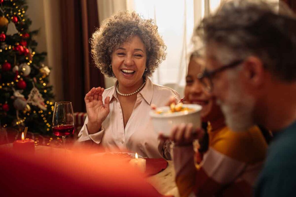 A woman smiling to her family at the table during a holiday get-together