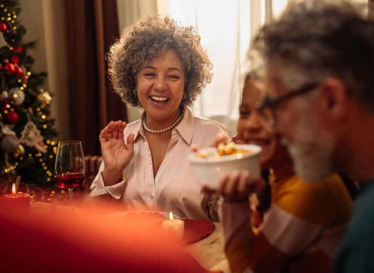 A woman smiling to her family at the table during a holiday get-together