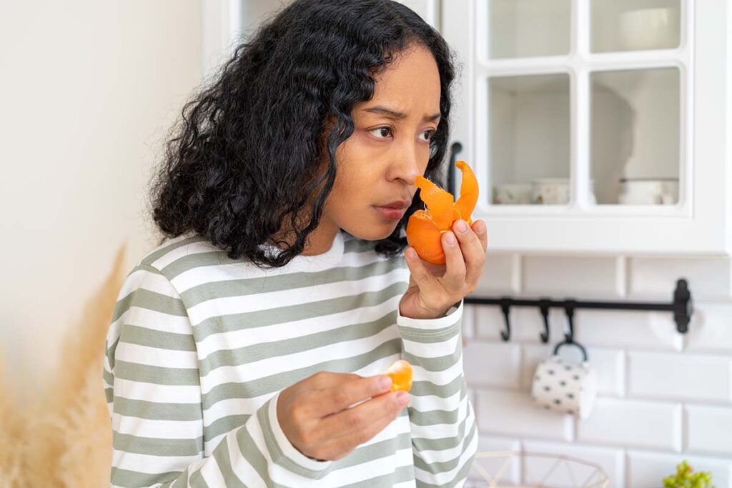 A woman smells an orange