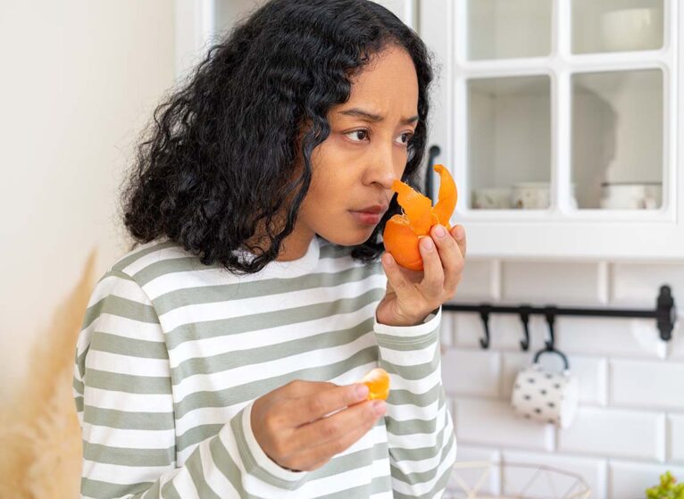 A woman smells an orange