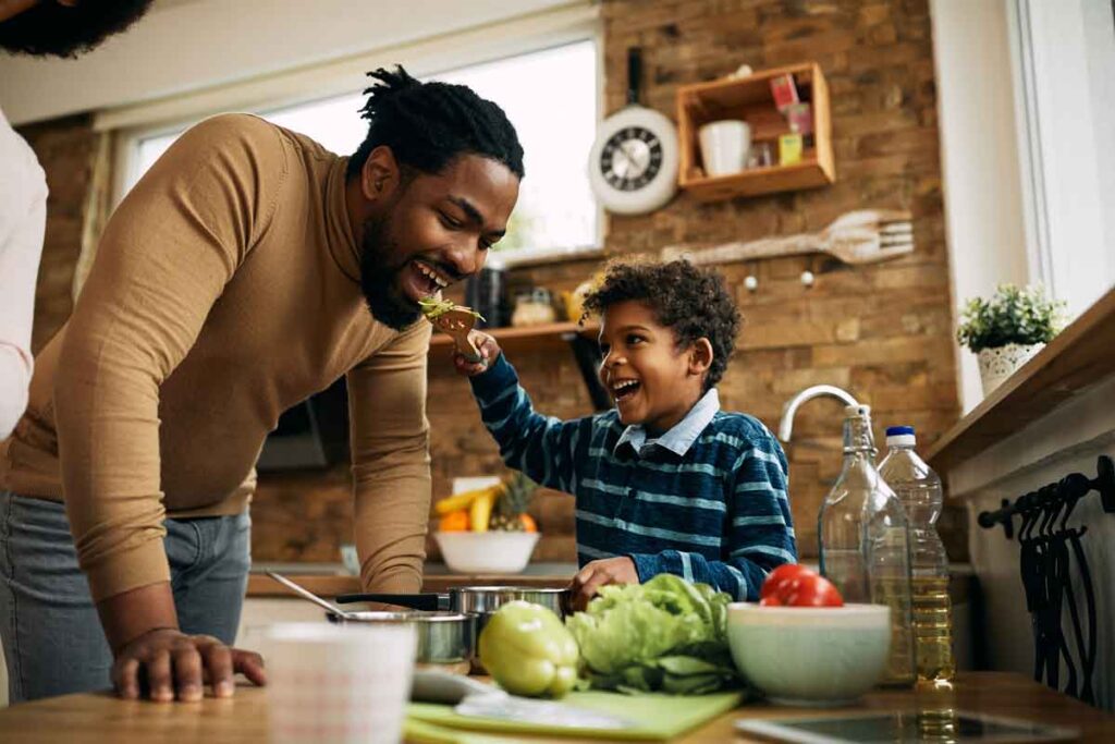 A young boy feeding heart healthy food to his father on a utensil