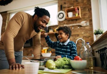 A young boy feeding heart healthy food to his father on a utensil