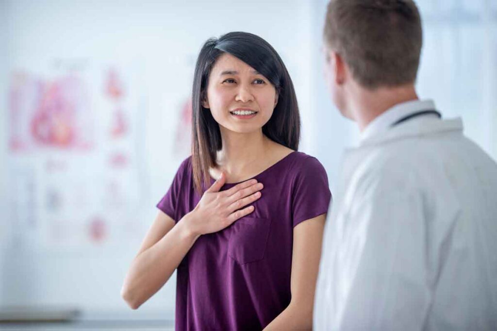 A woman talking to a provider with her hand over her heart. In 2025, heart & vascular disease remains the leading cause of death.