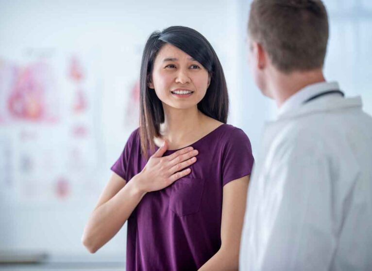 A woman talking to a provider with her hand over her heart. In 2025, heart & vascular disease remains the leading cause of death.