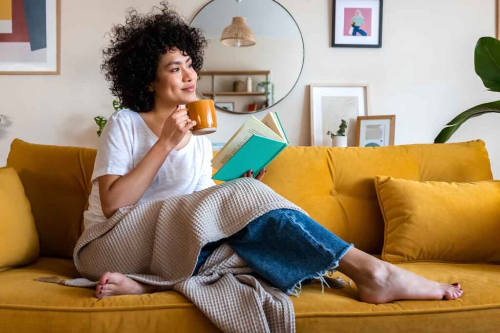 A woman with dark curly hair holding a cup of coffee and looking to the right