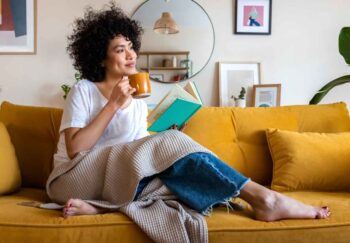 A woman with dark curly hair holding a cup of coffee and looking to the right