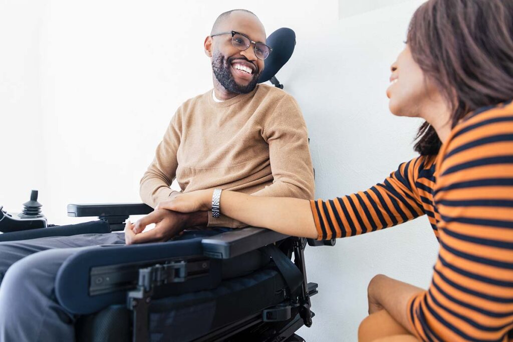 a man in a wheelchair with his wife beside him