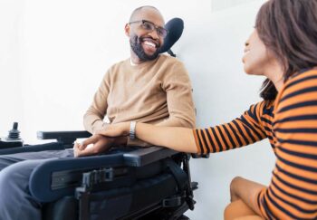 a man in a wheelchair with his wife beside him