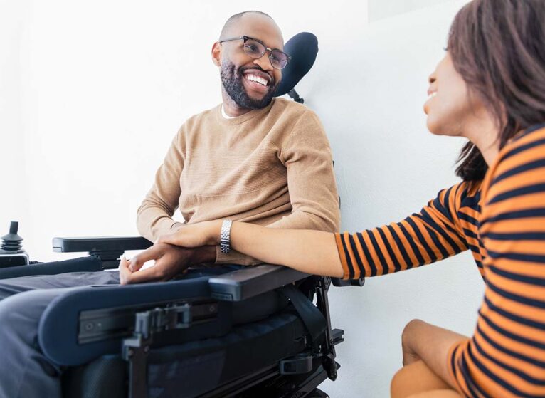 a man in a wheelchair with his wife beside him