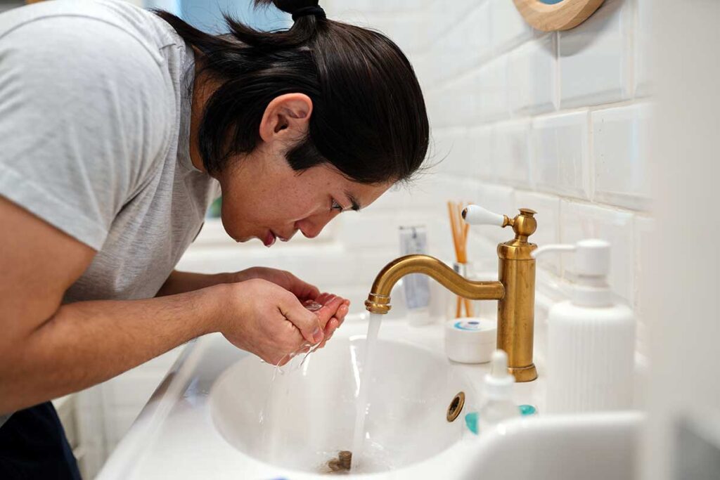 a woman splashes water on her face to calm her vagus nerve and anxiety