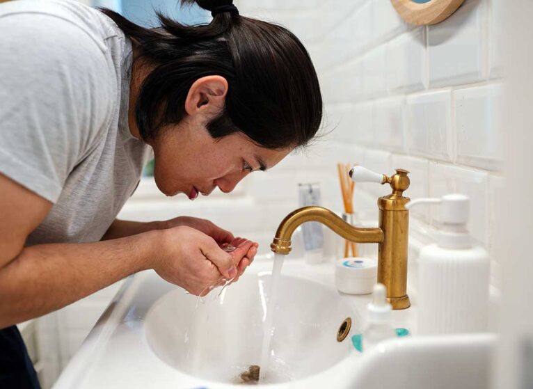 a woman splashes water on her face to calm her vagus nerve and anxiety