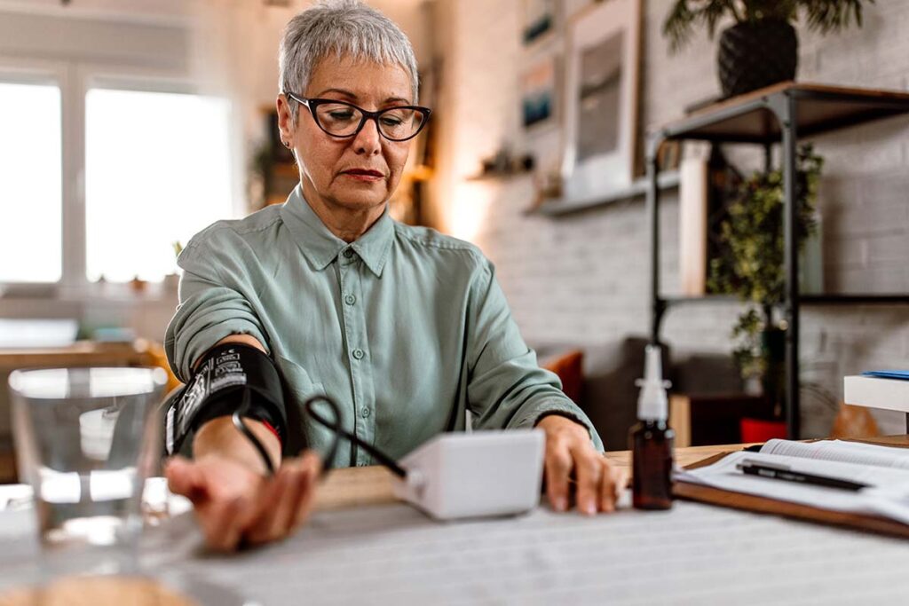 an older person takes their blood pressure at home