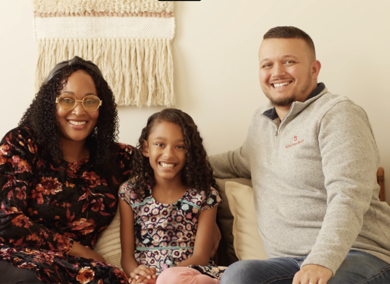Faith sits between her two parents on the couch