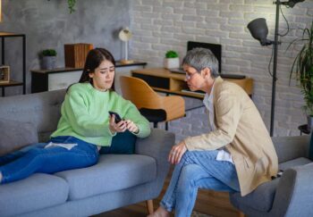Teenager shows their cell phone to adult with concerned face. Health issues on social media have led to a rise in self-diagnosis