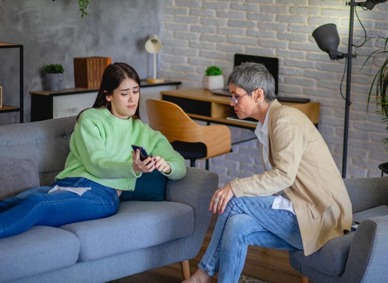 Teenager shows their cell phone to adult with concerned face. Health issues on social media have led to a rise in self-diagnosis
