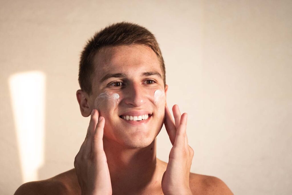 A man applies sunscreen to his face