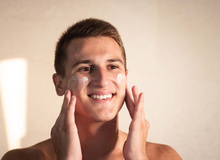 A man applies sunscreen to his face