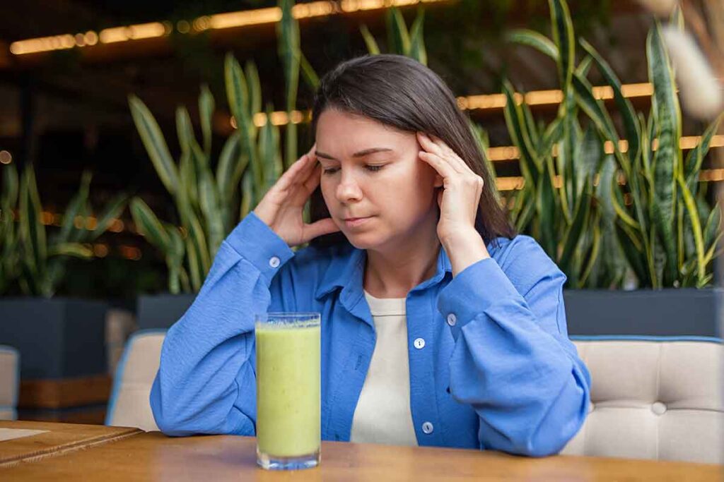 Know the anorexia heart failure signs before things get worse. A girl stares at a green smoothie with worry.