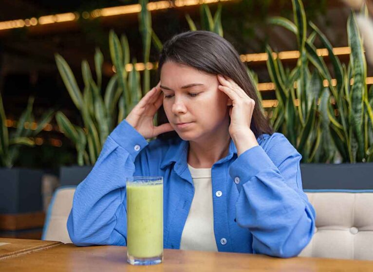Know the anorexia heart failure signs before things get worse. A girl stares at a green smoothie with worry.