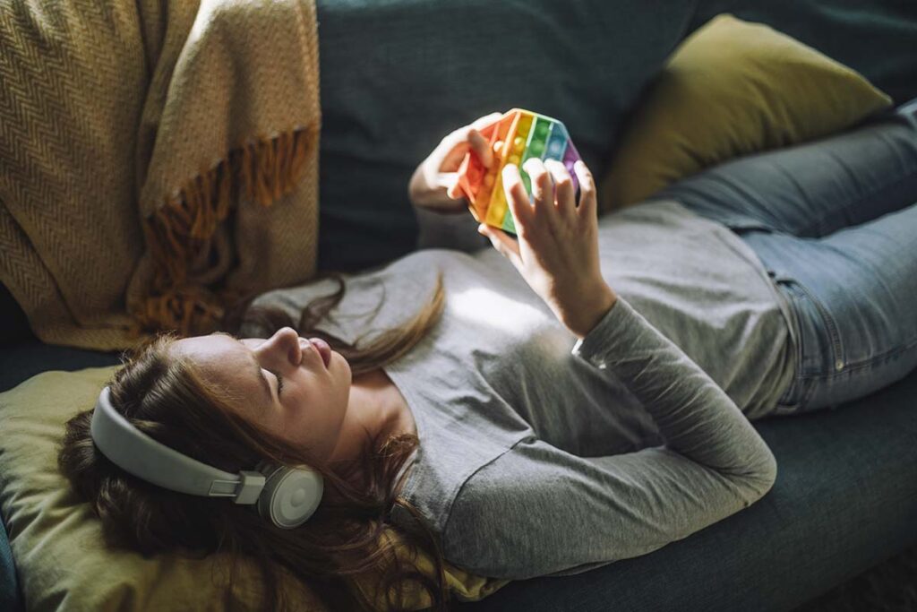 Teenage girl listens to music and plays with fidget toy