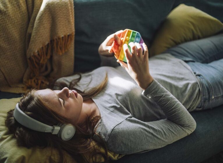 Teenage girl listens to music and plays with fidget toy