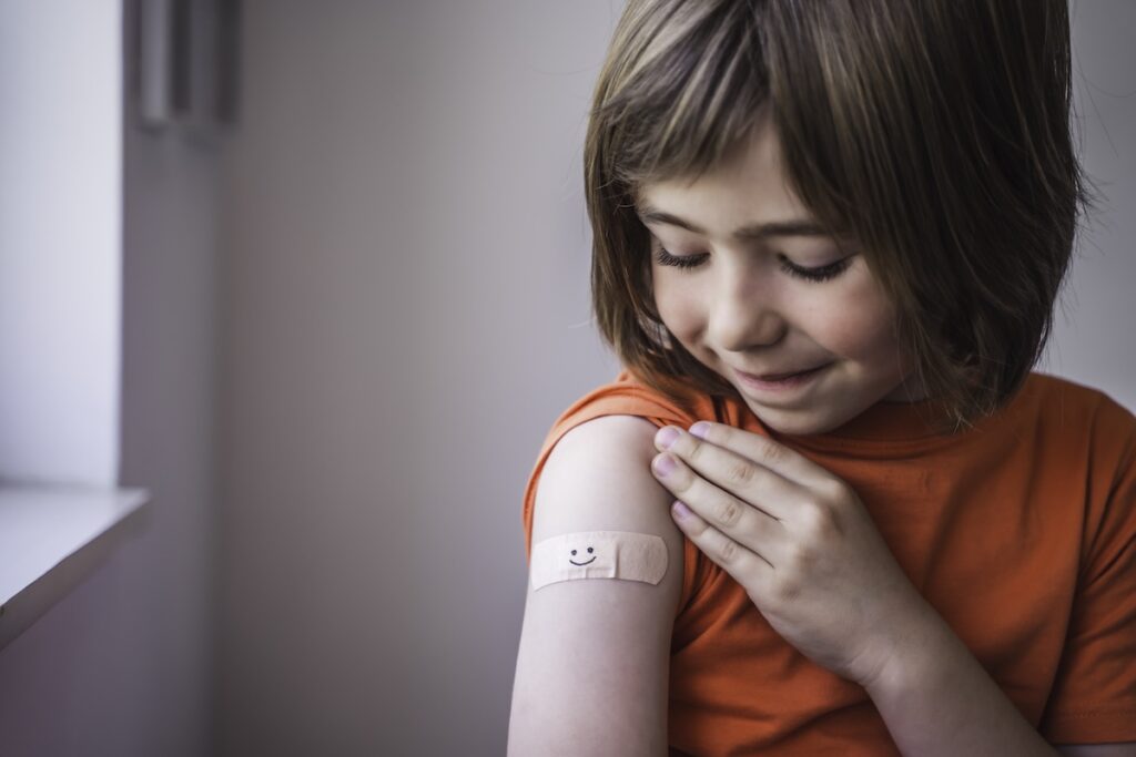 Happy child gets vaccines and smiley bandaid