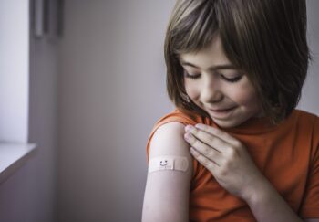 Happy child gets vaccines and smiley bandaid